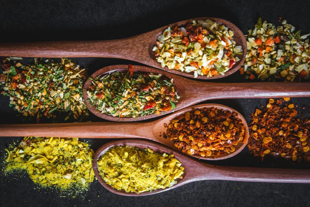 Vibrant spices and herbs displayed in wooden spoons, perfect for culinary inspiration.